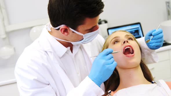 Dentist examining a female patient with tools