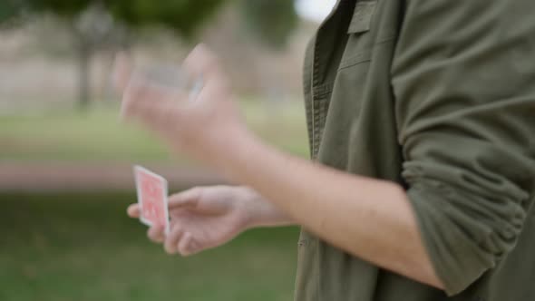 Close Up Shot of the Hands of a Male Street Magician Playing with Cards While Passing a Beautiful