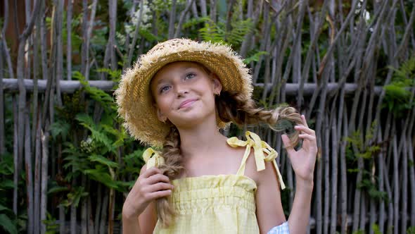 Portrait of Adorable Happy Teen Girl with Braids Posing in Wicker Hat