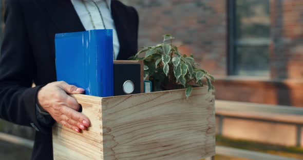 Side Close Up View of Female Office Worker in Formal Wear Carrying Box with Her Belongings While