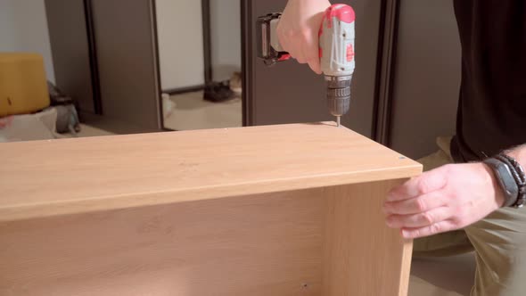 Furniture Maker Tightens a Screw Into the Cabinet Body with an Electric Drill