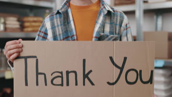 Food Bank Worker Holding Banner with Phrase Thank you