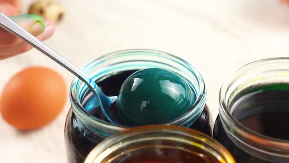 a Child of Caucasian Ethnicity Paints Easter Eggs with a Metal Spoon and Puts Them in Glass Jars