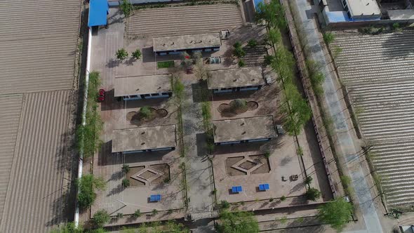 Aerial View of Small Poor Village with School in the Middle of Dry Farmland