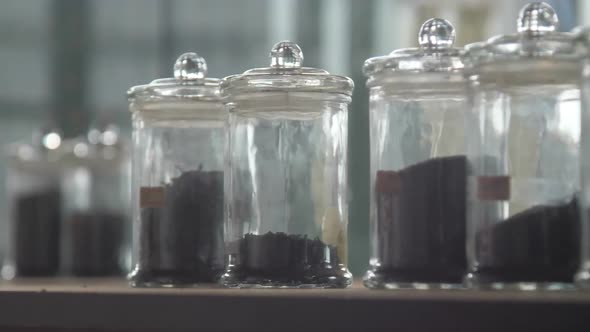 Person Hand Takes Transparent Bottles with Tea Sorts