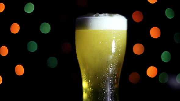 A Glass of Cold Beer on a Black Background with Colored Lights