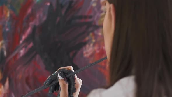 Artist Holds Brush Looking at Canvas with Abstract Drawing