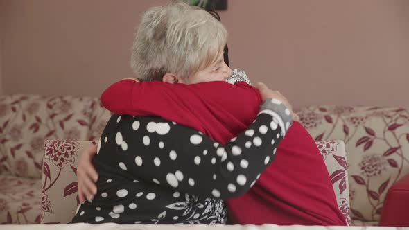 Big hug between generations: grand-daughter abraces strongly her grandmother