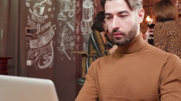 Handsome Young Man Sipping Some Coffee While Working on His Computer