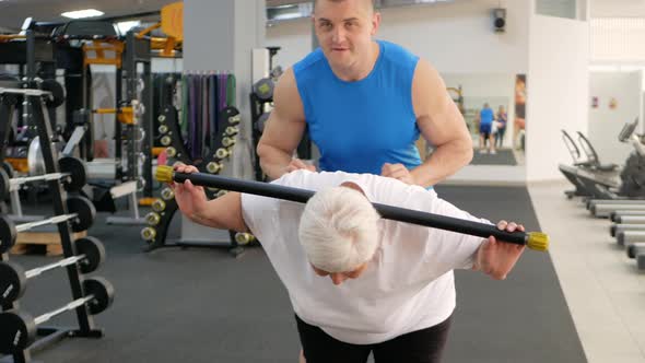 Elderly Woman Does a Stretching Exercise in the Gym