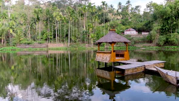 Idyllic bamboo hut pontoon with traditional thatched roof on the water surrounded by trees in Timor