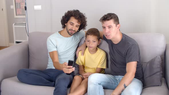 Two Focused Dads and Son Studying Remote Control for New TV