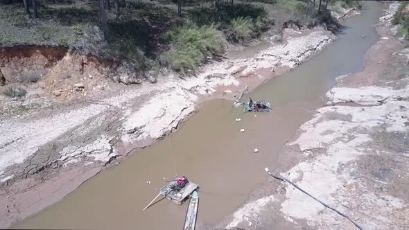 Skillful Grit Miner Stands on Extracting Equipment in River
