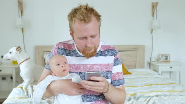 a man with a baby in his arms looking for his symptoms on the phone