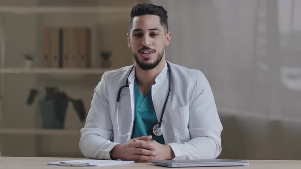 Cheerful Smiling Young Man General Practitioner Doctor with Stethoscope Talking at Camera Explaining