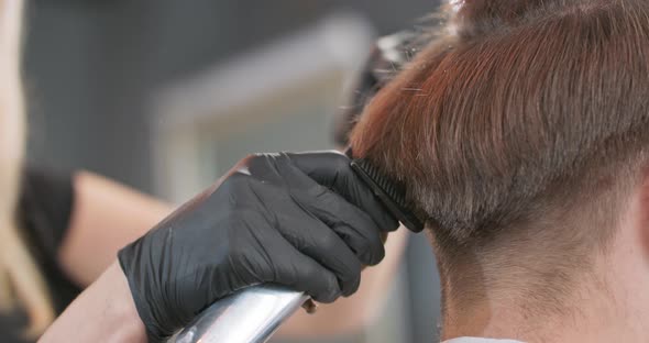 Closeup of Female Barber's Hands Who Clippers with Hair Clipper and Comb Young Bearded Man's Hair