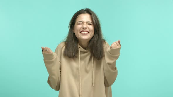 Cheerful Girl in Hoodie Rejoicing Hear Amazing News and Smiling with Joy Making Fist Pump Gesture