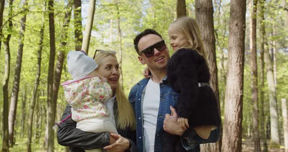 Happy Mom Dad With Small Children In His Arms In The Park