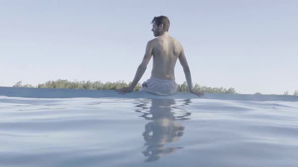 Man sitting on edge of pool