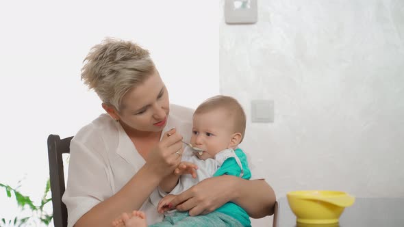 Woman Feeding Toddler with Porridge on Kitchen