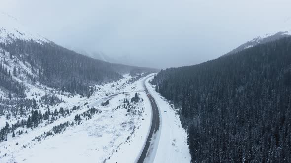 Bird's eye view of forest, mountains, fog and snow in wintertime in Kananaskis, Alberta, Canada