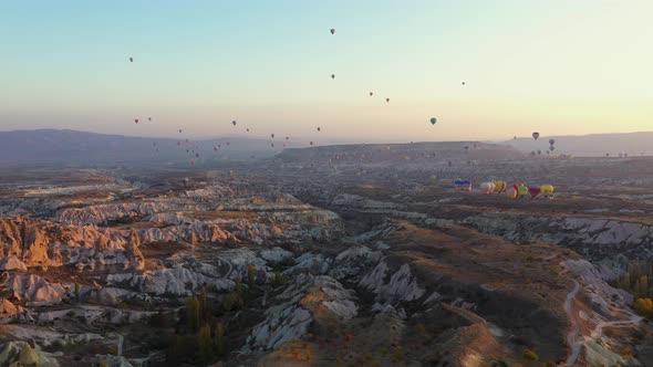 Colorful Hot Air Balloons Flying Over Rocky Landscape in the Morning.