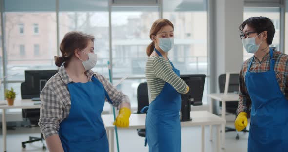 Professional Office Cleaning Janitors in Safety Mask Bumping Elbows at Workplace