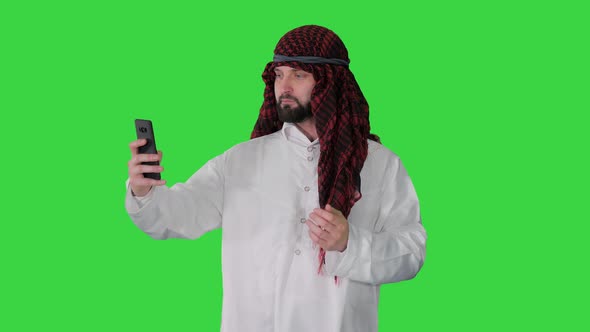 Arabian Man Walking and Making a Selfie with His Phone on a Green Screen, Chroma Key.