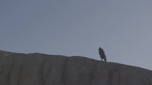 A Tired Traveler in a Raincoat Walks the Ridge on a Sultry Day