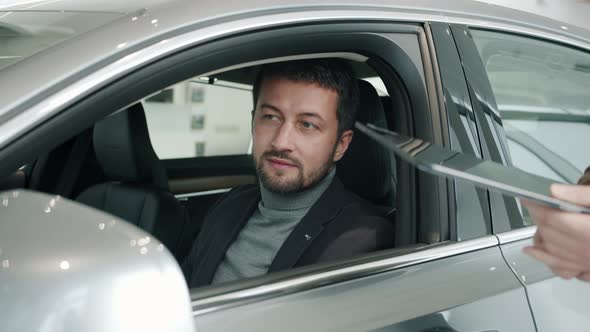 Car Dealership Client Getting Key Fob From Sales Manager Sitting Inside New Car