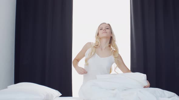 Young woman in the bed. Beautiful blond girl wakes up. Morning in the bedroom.