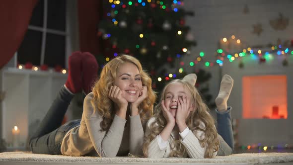 Female and Girl Lying Under Christmas Tree, Looking to Camera and Smiling, Decor