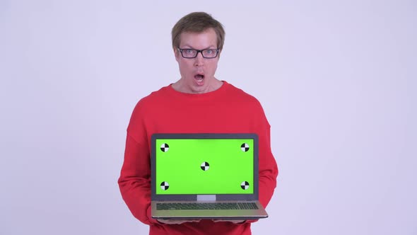 Young Handsome Man Showing Laptop and Looking Shocked