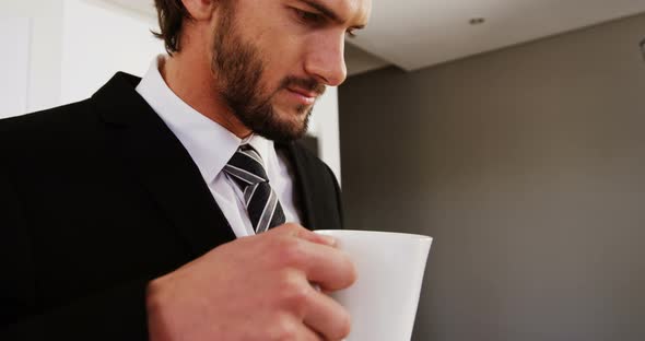 Businessman reading newspaper while having coffee in kitchen