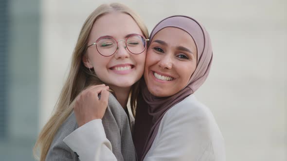 Two Happy Smiling Diverse Young Women Friends or Colleagues Hugging Happy to Meet