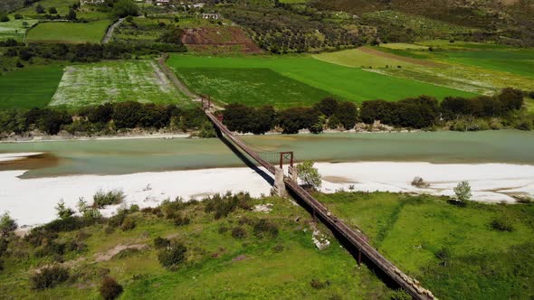 Aerial Top Down View of Sheep and Rams Crossing the Mountainous River on the Bridge with Shepherd in