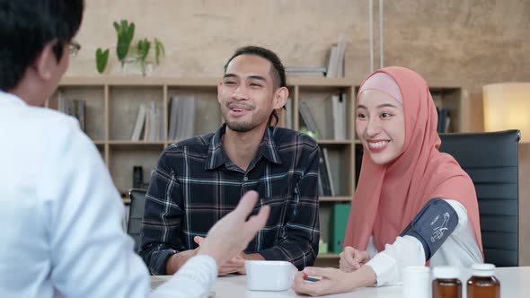 Young Muslim couple consulting with professional Asian male doctor.