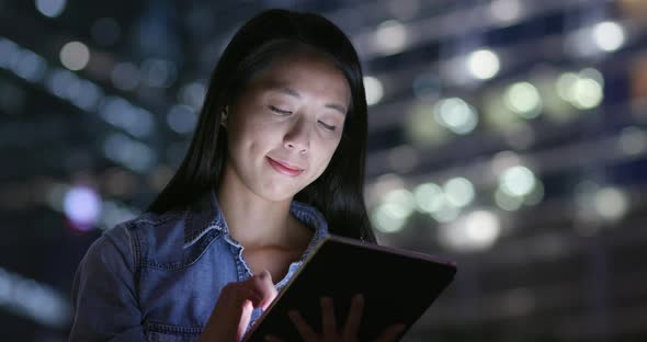 Woman use of tablet computer in city at night