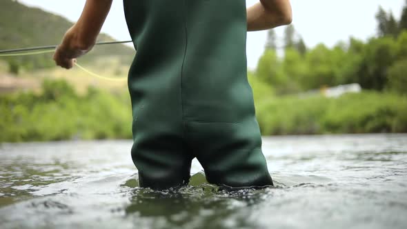 Shot of a male fisherman wearing waders while Fly Fishing. He is standing in the middle of the Provo