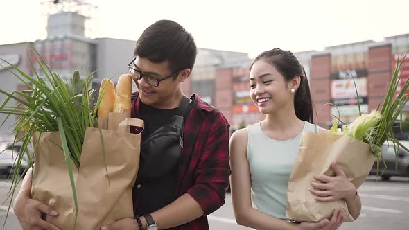 Smiling Vietnamese Couple Going from the Supermarket with Bags Full of Various Food