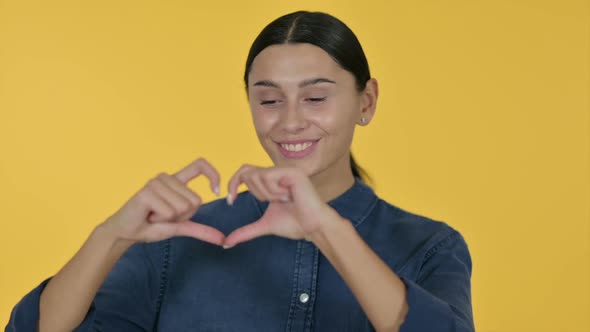 Latin Woman Heart Sign By Hand Yellow Background