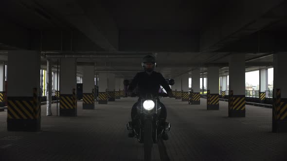 Man Riding Scrambler Motorbike Though the Multilevel Parking