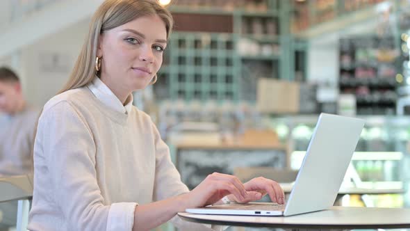 Laptop Use By Young Woman Smiling at Camera in Cafe