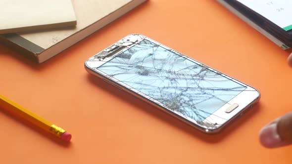 Man Hand Holding Broken Smart Phone on Orange Background