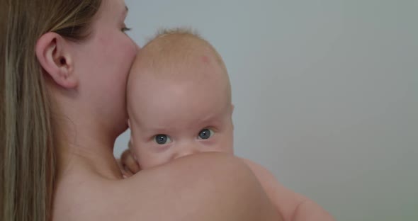 Happy Mother Holds a Little Baby Boy on Background