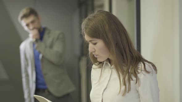 Close-up of Beautiful Young Caucasian Woman Looking Through Documents As Handsome Man Checking His