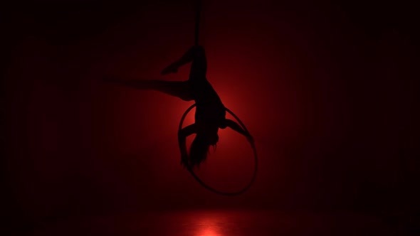 Aerial Acrobat in the Ring. A Young Girl Performs the Acrobatic Elements in the Air Ring on Red