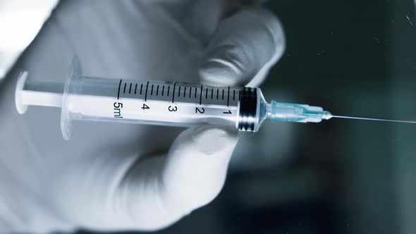 Healthcare worker or doctor placing syringe on table in laboratory. Medicine concept.