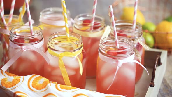 Raspberry lemonade garnished with fresh lemon and raspberries in drinking mason jars.