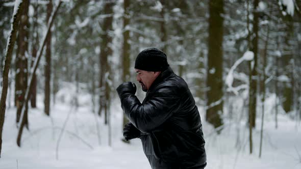 Adult Man is Training in Winter Forest Boxing with Invisible Enemy Training Hands Punches